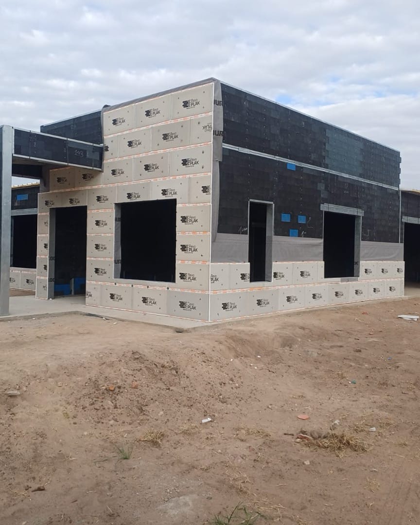 Obra real — placa Revo Plak atornillada en seco sobre el bloque, terminación exterior